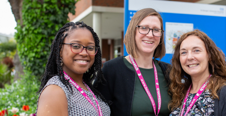 Three female staff members standing together outside a hospital entrance